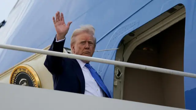 Donald Trump waving as he enters through the doors of Air Force One