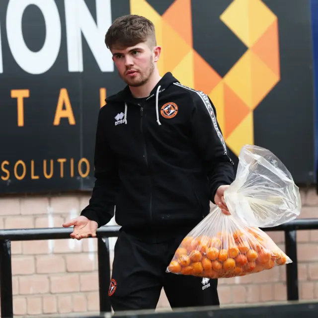 A Dundee United member of staff carries a big bag of tangerines