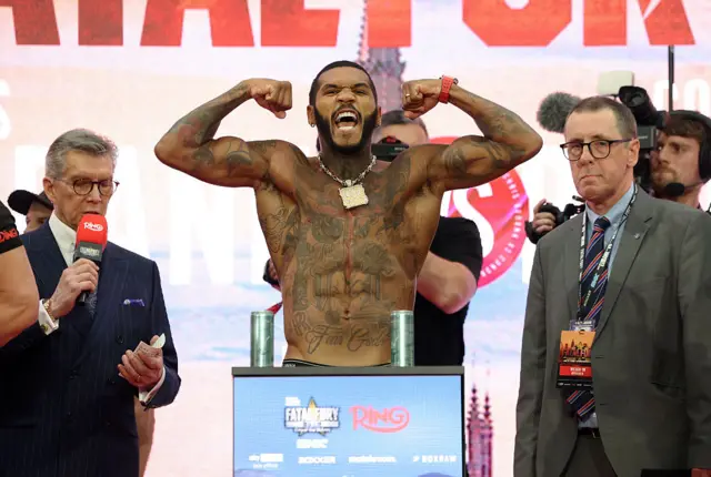 Conor Benn holds up his arms as he stands on the scales at a weigh-in