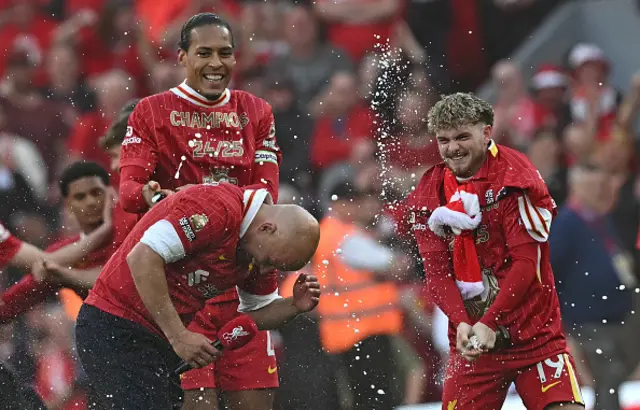 Arne Slot reacts as Virgil van Dijk (L) and Harvey Elliott spray him with champagne