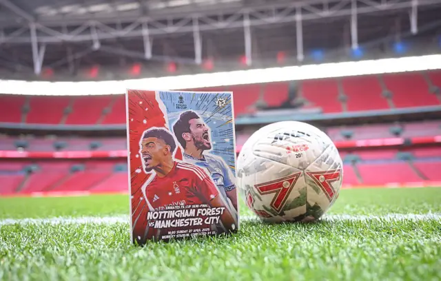 A match programme from the FA Cup semi-final between Nottingham Forest and Manchester City next to a football on the pitch at Wembley