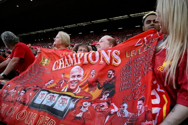 Fans of Liverpool hold up a banner in support