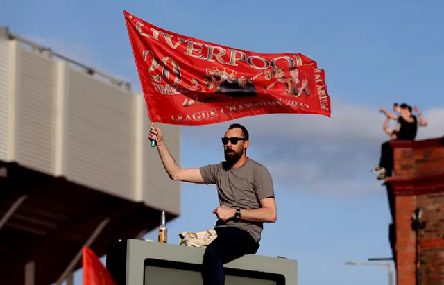 A fan of Liverpool waves a flag outside of the stadium