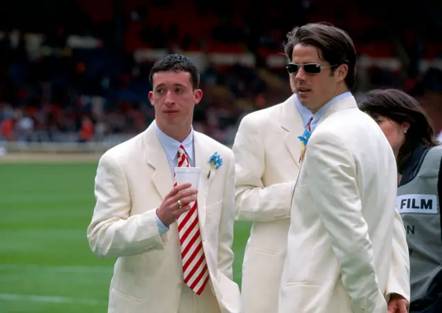 Robbie Fowler and Jamie Redknapp wearing white suits on the pitch at Wembley