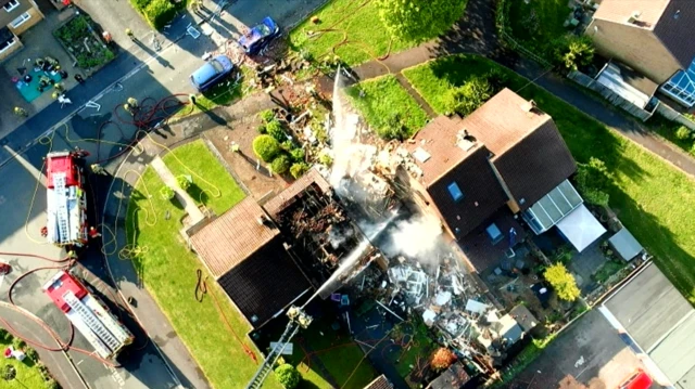 A drone image showing the aerial view of the top of the burnt home. The entire property has been burnt to the ground but the neighbouring homes seem structurally intact besides a burnt roof.