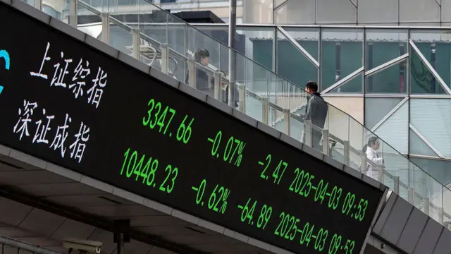 An electronic ticker displays the figures for the SSE Composite Index, top, and the SZSE Composite Index on a footbridge in Pudong's Lujiazui Financial District in Shanghai