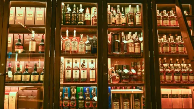 Bottles of Irish whisky on display insider a wooden case with glass doors and internal light