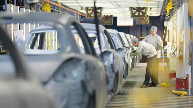Car plant workers on production line