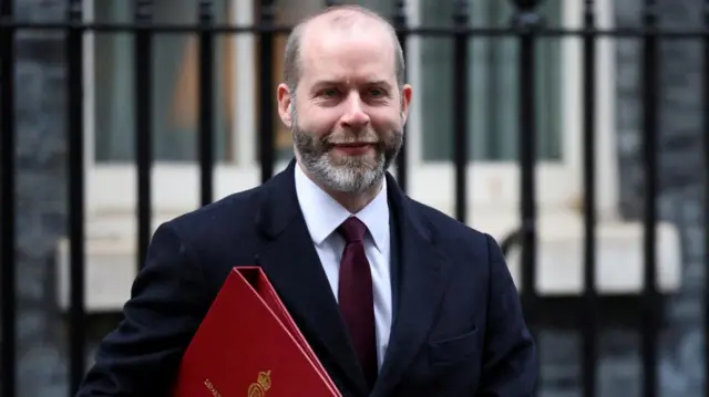 A file photo of Jonathan Reynolds - he is carrying a red folder and smiling