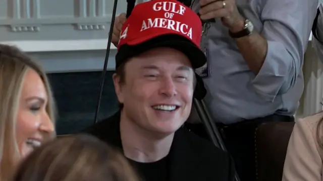 Elon Musk wearing two caps one on top of the other