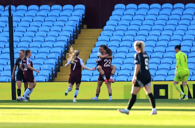 Villa players celebrate as Arsenal players trudge back to their positions for kick off
