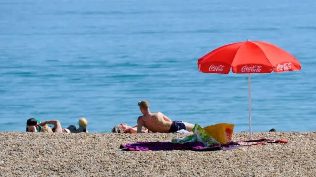 Four people lying on the beach, with the sea in the background