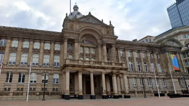 The front of a large beige building with pillars around the entrance way