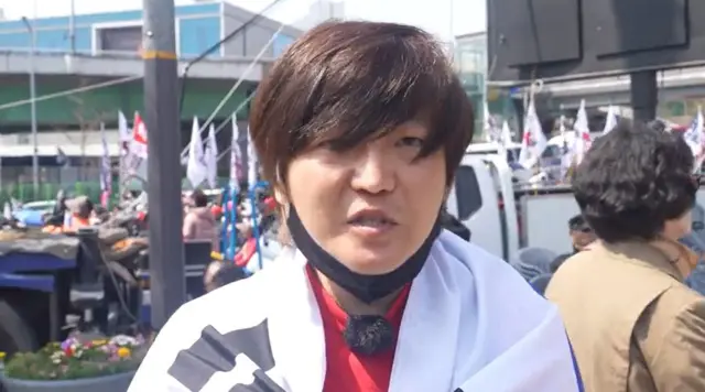 A man with brown side-swept hair looks at the camera