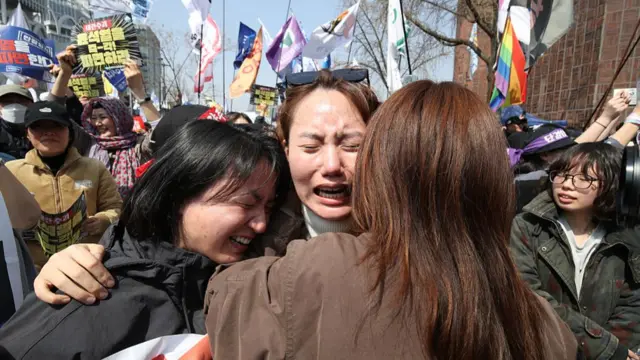 Women embrace and cry