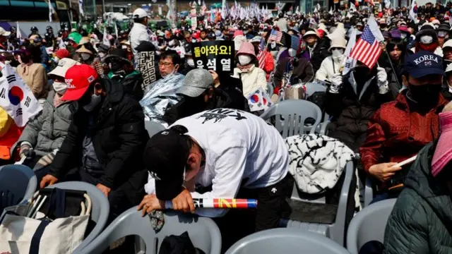 A man bends over a chair among a sea of protesters