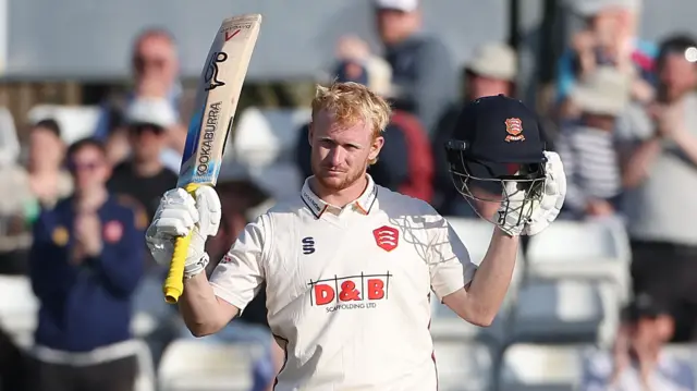 Jordan Cox raises his bat after scoring a century for Essex against Surrey