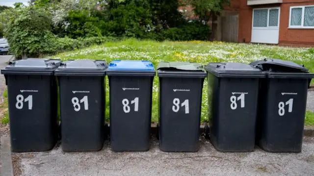 A row of black bins with white lettering on them