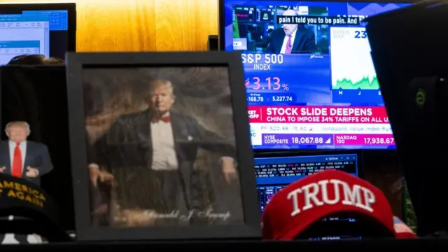 A picture of Trump, and a red hat reading Trump, sits in front of a TV screen with the headline: 'Stock slide deepens'.