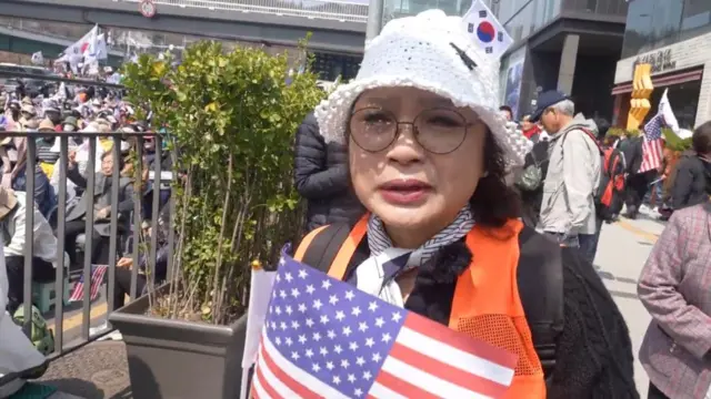 Won Bog-sil wearing a white hat and holding the US flag