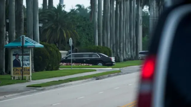A vehicle drives on a road in Florida, with palm trees in view.