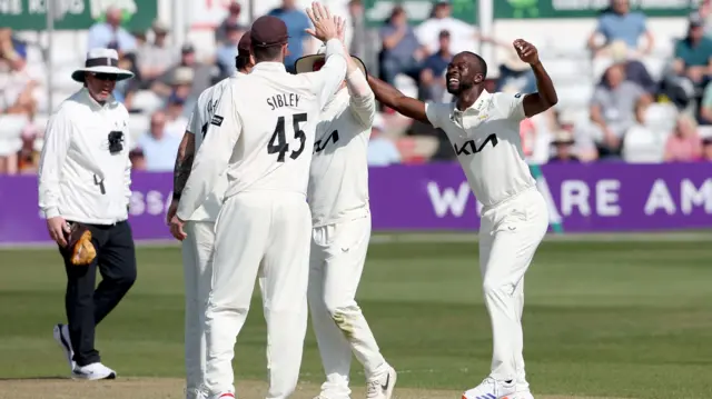 Kemar Roach celebrates taking the wicket of Tom Westley with Surrey team mates