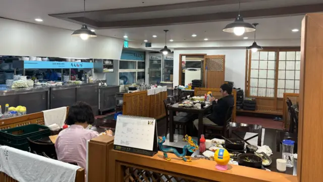 Two people, sitting at different tables, dine at the restaurant