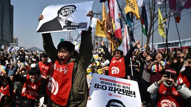 A man cheers as he raises a poster of Yoon
