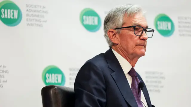 Jerome Powell in a suit in front of a white backdrop