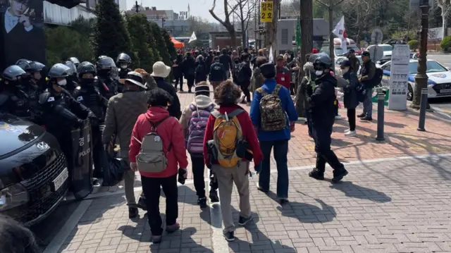 Backview of a group of elderly people carrying backpacks and walking away