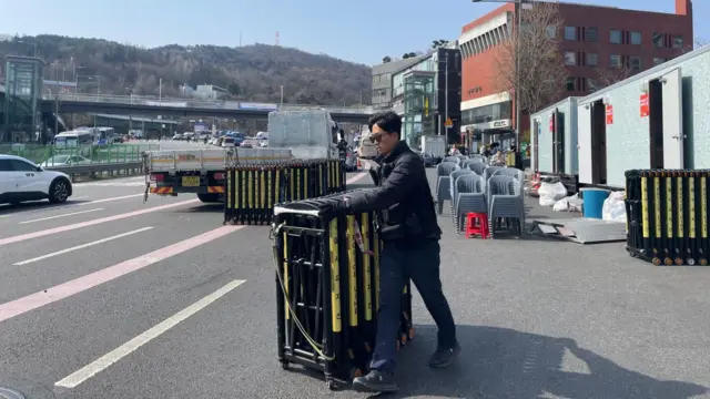 A man wheels a retractable barricade on the road