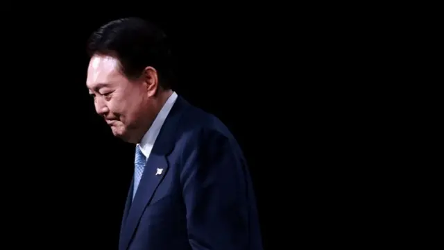 Sideview of Yoon against a dark background.