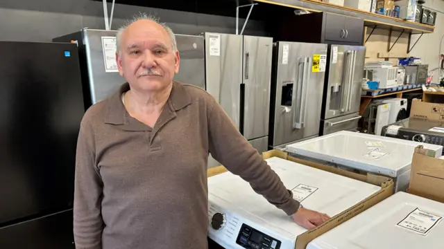 Pat Muscaritolo stands in front of appliances, including fridges and washing machines.