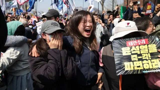 Two girls cheer among a crowd of protesters