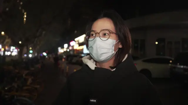 A woman wearing a mask speaking