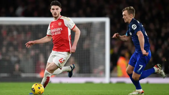 Declan Rice of Arsenal runs with the ball whilst under pressure from James Ward-Prowse of West Ham