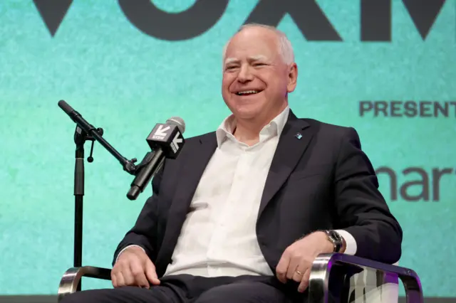 Tim Walz speaks on a stage at a podcast show