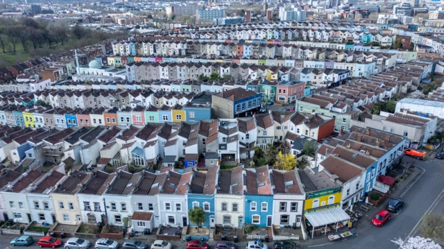 Some of Bristol distinctive multi-coloured Victorian-era houses arranged in terraced streets in Totterdown are viewed from the air.