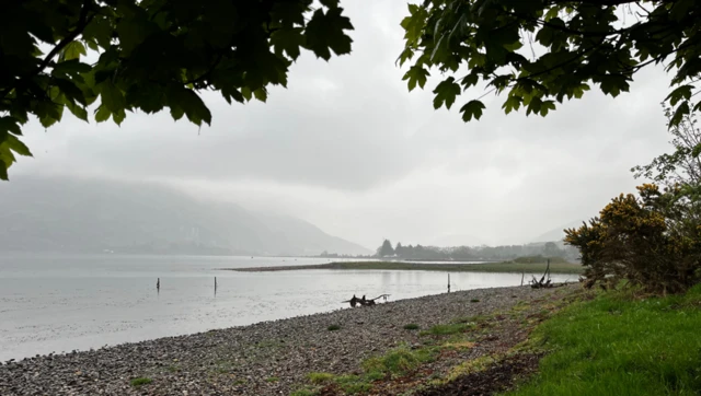 Low clouds over the water and pebbled beach at Taynuilt
