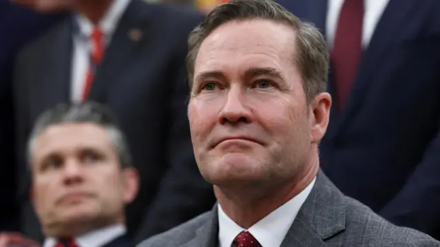 Mike Waltz is wearing a grey stripped suit over a white shirt and burgundy tie.