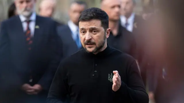Ukrainian President Volodymyr Zelensky speaks wearing a black top.