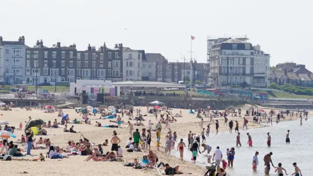 A busy beach with houses in the backgorund