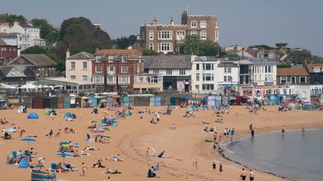 A wide shot of groups of people sat on a beach