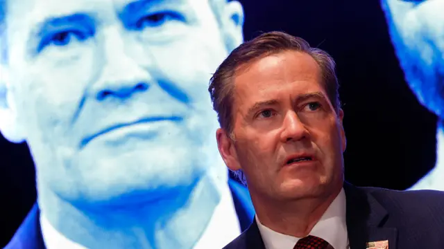 Mike Waltz speaks at a news conference, wearing a suit and tie.