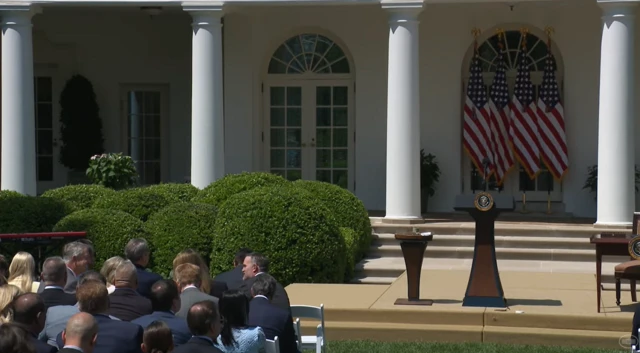 Exterior shot of White House garden, rows of seats filled by people.