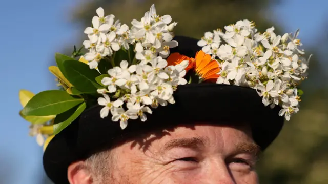 A man wears a hat with flowers in it
