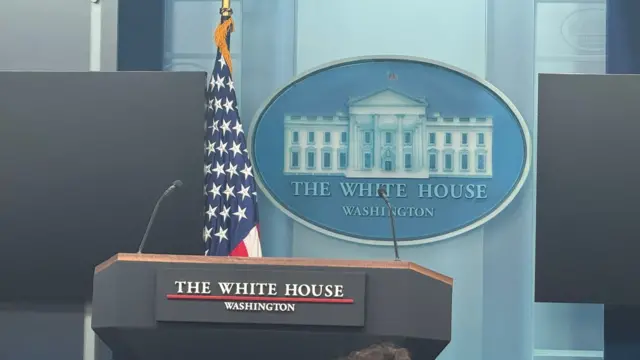 A podium at a White House briefing, with the American flag in the background.