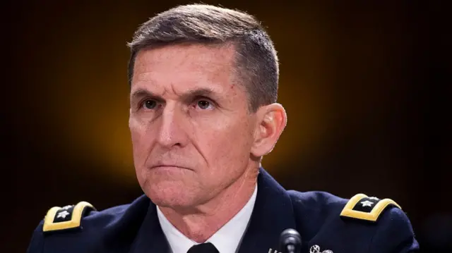 Michael Flynn sits in front of a mic while wearing a ceremonial army uniform
