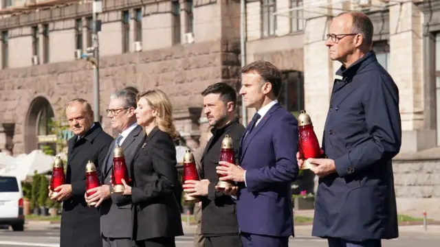 German Chancellor Friedrich Merz, French President Emanuel Macron, Ukrainian President Volodymyr Zelenskiy and his wife Olena Zelenska, Britain's Prime Minister Keir Starmer, and Poland's Prime Minister Donald Tusk visit Maidan square and hold candles, wearing formalwear.