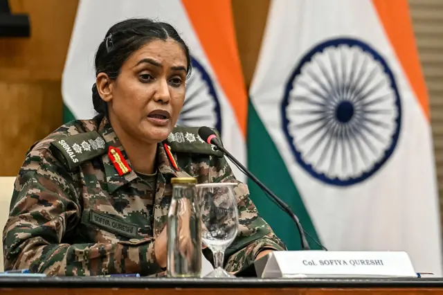 Indian offical briefs in front a flag